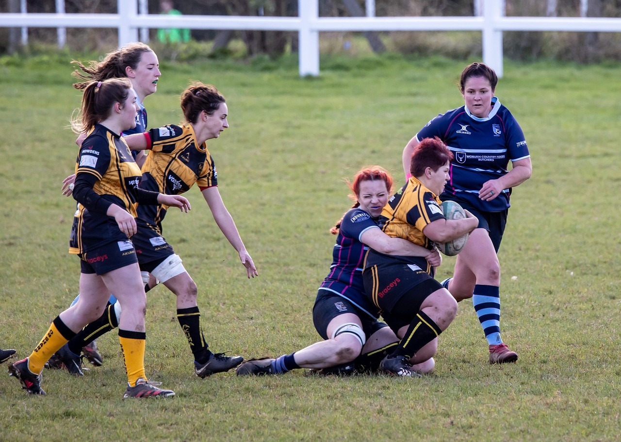 A group of women playing a rugby match on a grass field.