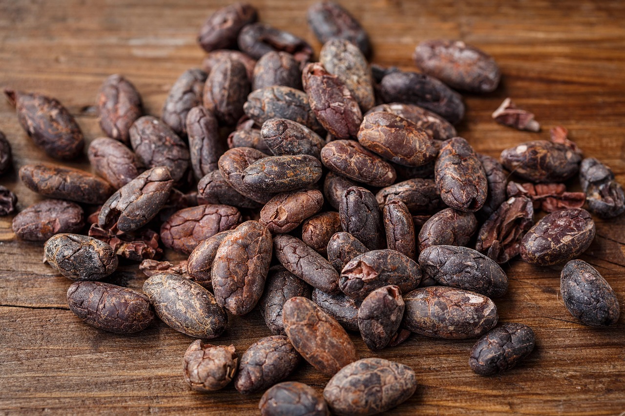 A pile of raw cocoa beans on a wooden surface
