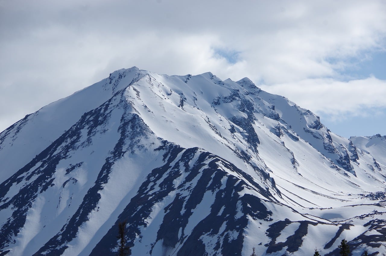 A snow-covered mountain peak in Alaska, representing the landscape where the ancient camp was discovered.