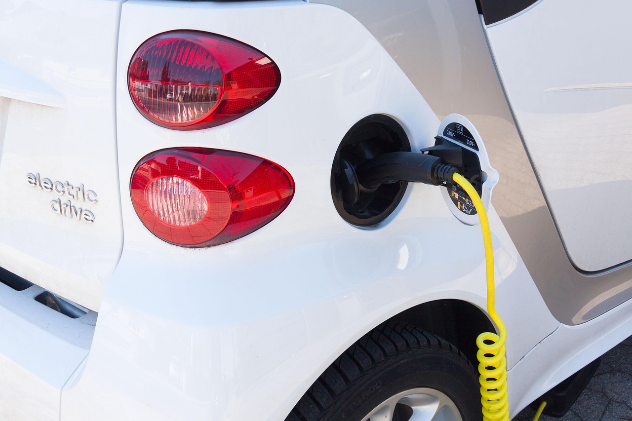 A close-up of an electric car being charged with a yellow cable.