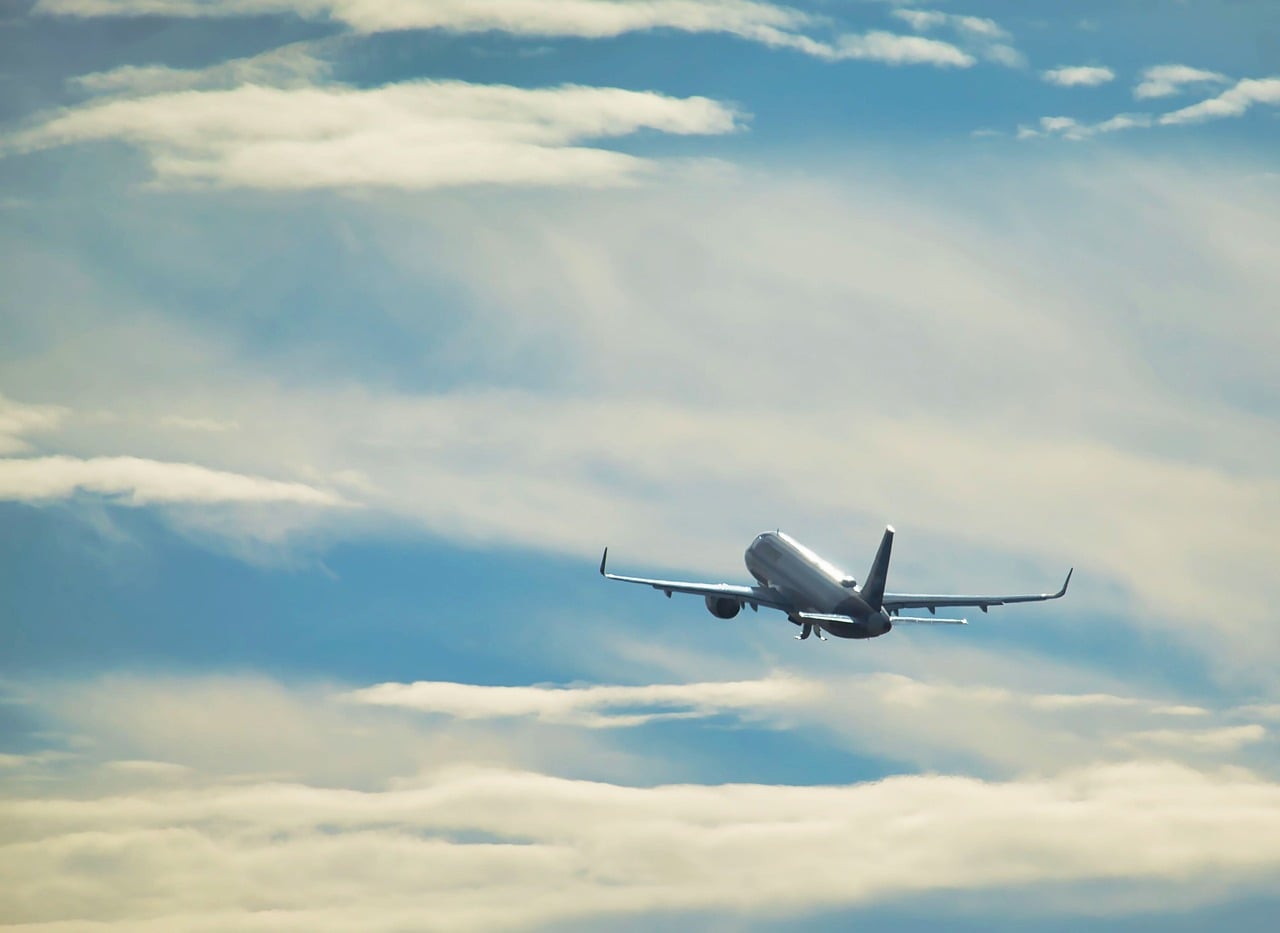 A commercial passenger airplane flying through a cloudy sky.