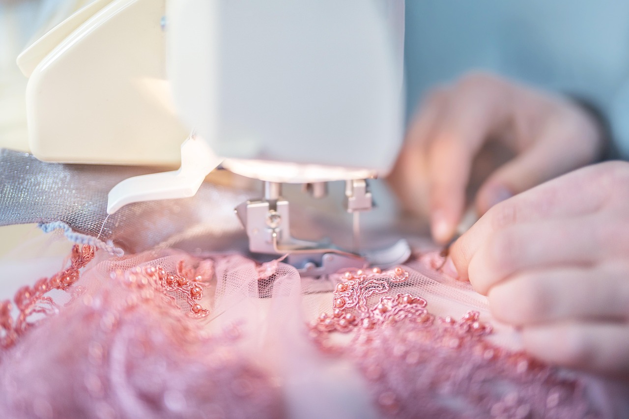 Close-up of a sewing machine stitching intricate pink lace fabric