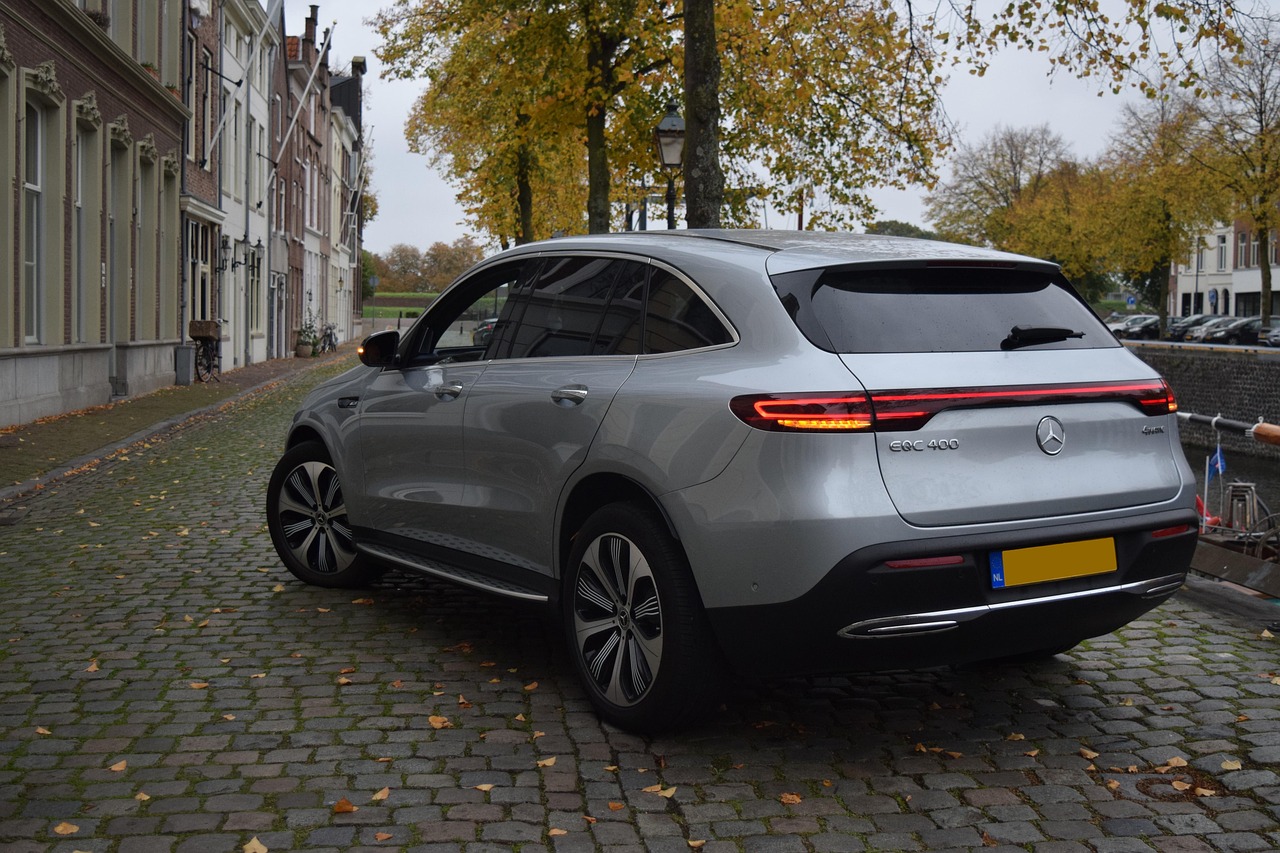 A silver electric SUV parked on a cobblestone street in a European town.